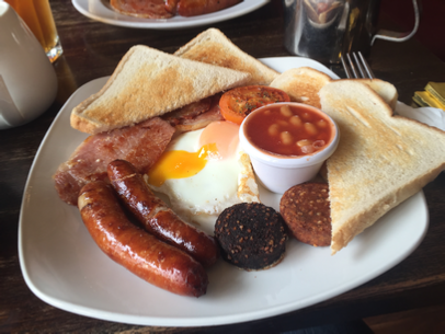 A traditional Irish breakfast with bangers, bacon, broiled tomato, beans, black & white pudding eggs and toast