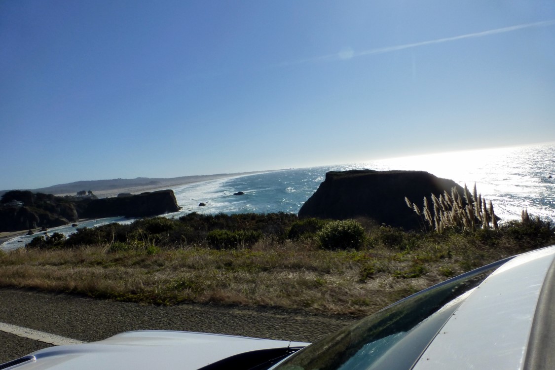 A long stretch of beach broken up with a spit of land. If you look closely, there is a house on the spit in the trees.