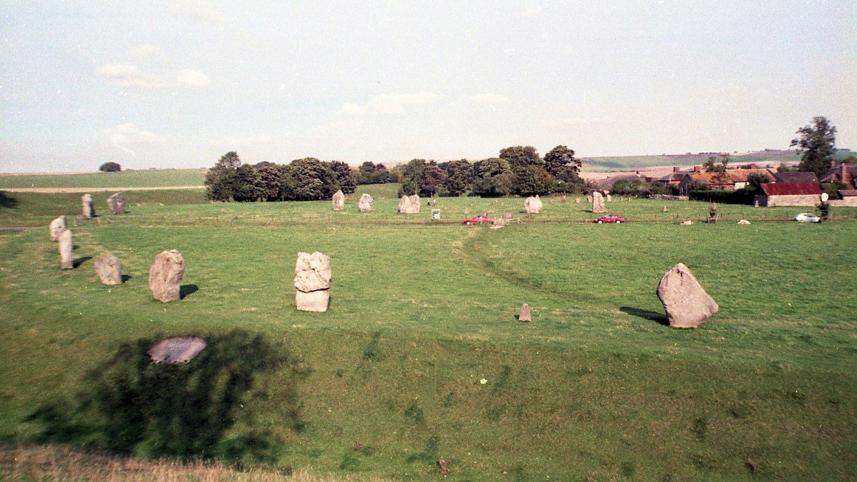 Avebury Stone Henge with the large ditch in the foreground. The Stones you see just beyond the red car is a smaller inner circle known as The Cove.