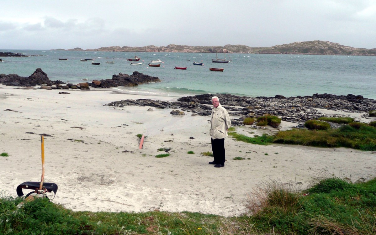 Alex on the beach with the azure water behind him